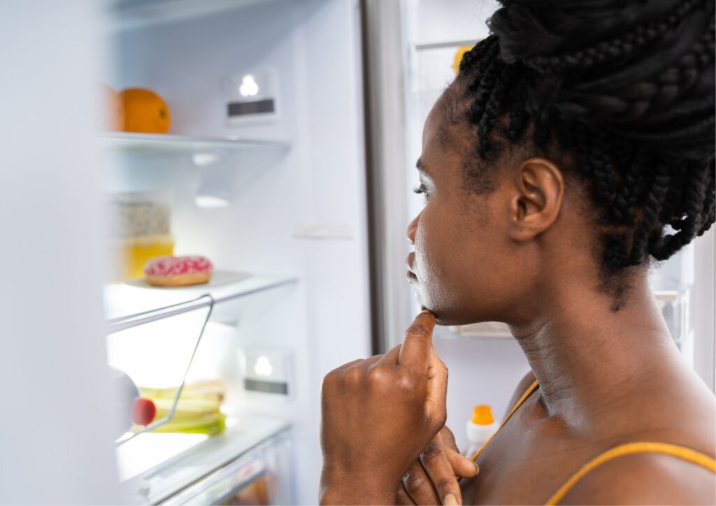Persona pensando frente al refrigerador, con expresión reflexiva o curiosa. 500 Recetas Keto Fáciles: cómo saber si es tu recetario ideal
