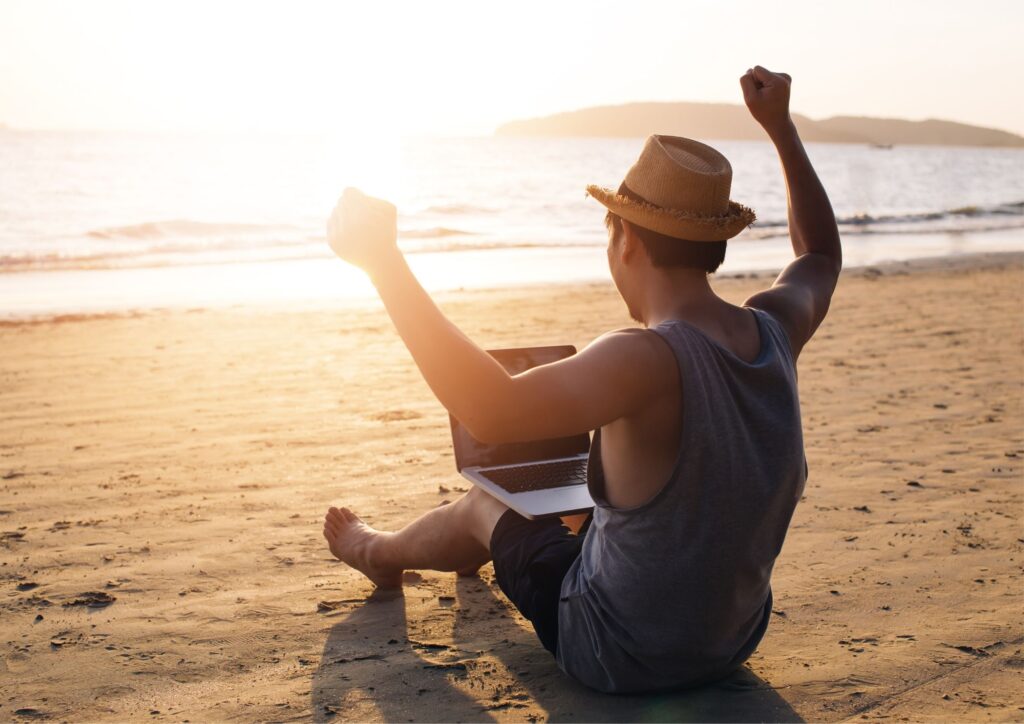 Una persona disfrutando de la libertad financiera, trabajando desde la playa